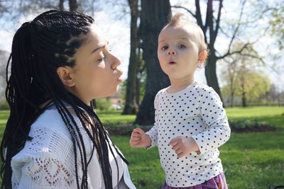 Mother with daughter against trees at park