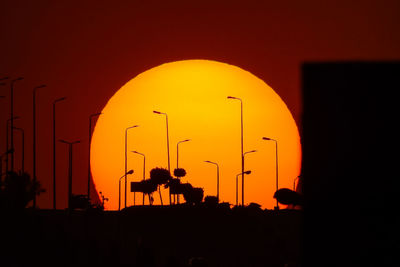 Silhouette men against orange sky during sunset