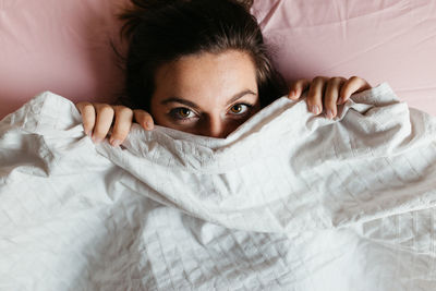 High angle portrait of young woman lying on bed