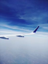 Airplane flying over clouds against blue sky