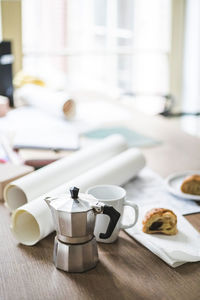 High angle view of teapot with documents rolled up on table