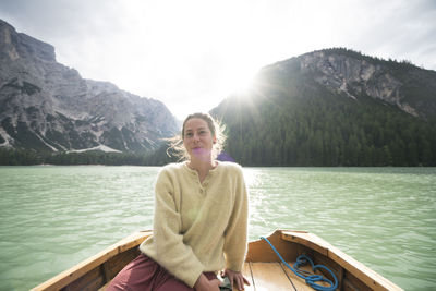 Woman sitting in boat on river amidst mountain against sky