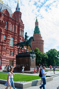 People walking in front of building against sky