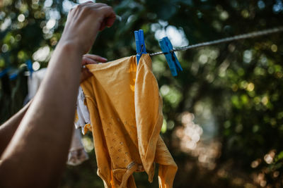 Cropped hand of woman drying clothes on clothesline