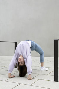 Girl bending over backwards by wall