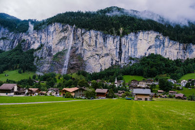Houses on field by buildings against mountains