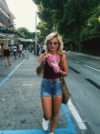 Portrait of beautiful woman standing on road in city