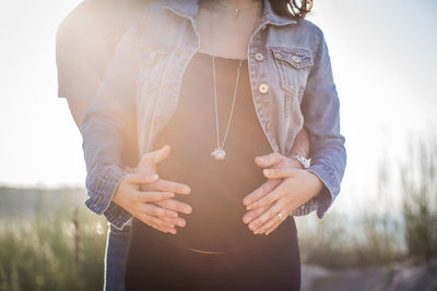 Midsection of pregnant woman with husband touching stomach