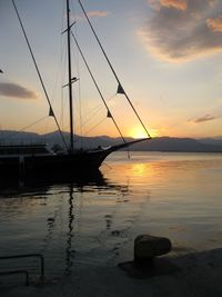 Sailboats moored on sea against sky during sunset