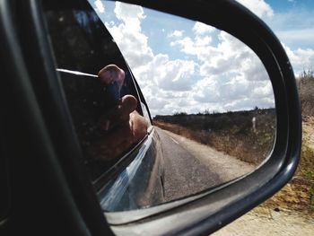 Reflection of man on side-view mirror of car