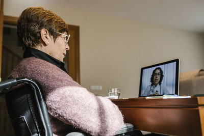 Disabled senior woman on video call with female doctor at home