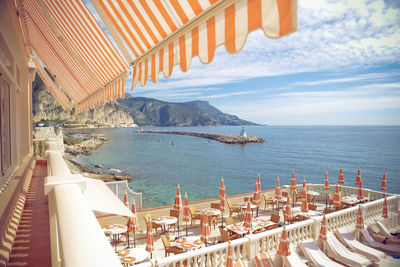 Tables and chairs with deck chairs in luxury hotel by sea against sky at monte carlo