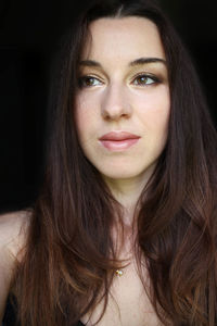 Close-up of beautiful mid adult woman against black background