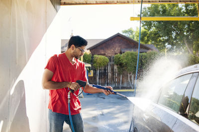 Man washing car in garage on sunny day