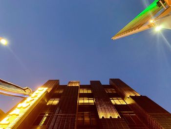 Low angle view of illuminated buildings against clear blue sky
