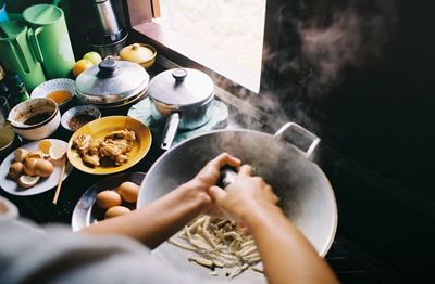 Cropped image of woman preparing food by window at kitchen