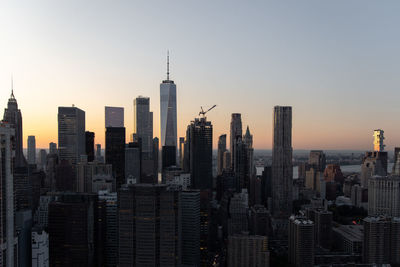 Modern buildings in city against sky during sunset