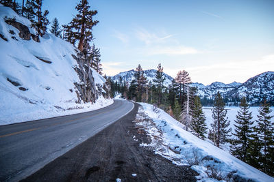 Road amidst snowcapped mountains against sky during winter