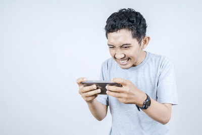 Young man using mobile phone against white background