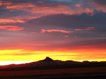 Scenic view of dramatic sky over silhouette landscape during sunset