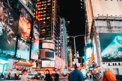 People on illuminated street in city at night