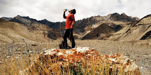 Full length of man standing on rock against sky