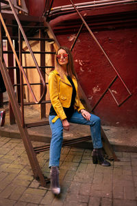 Full length portrait of young woman sitting on staircase