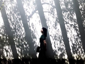 Side view of young woman standing by wall