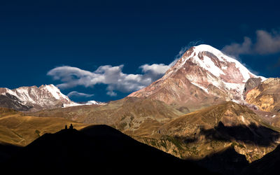 Scenic view of snowcapped mountains against blue sky