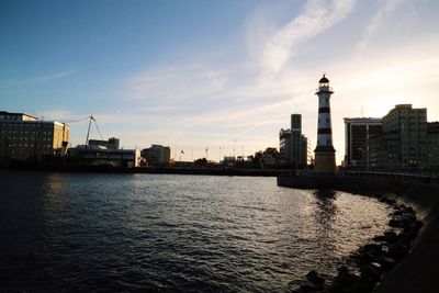 Lighthouse by sea against sky in city