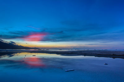 Scenic view of sea against dramatic sky during sunset