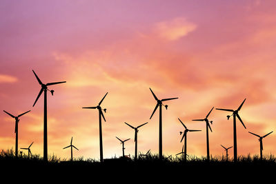 Silhouette of wind turbines on field against sky during sunset