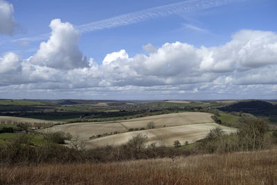 Scenic view of agricultural field against cloudy sky