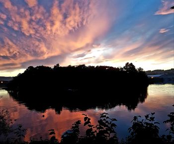 Silhouette trees by lake against sky during sunset