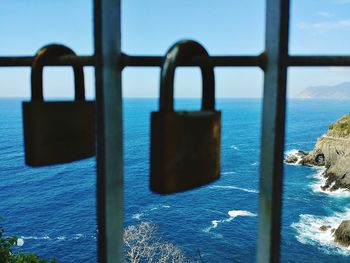 Close-up of padlock on railing against sea