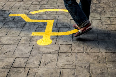 Low section of man walking on disabled sign at footpath