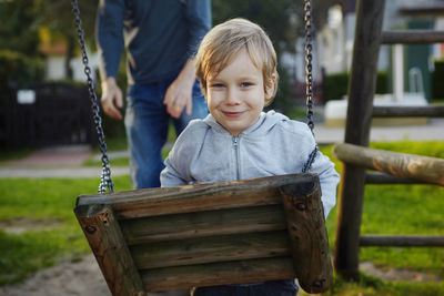 Portrait of smiling boy on swing at playground