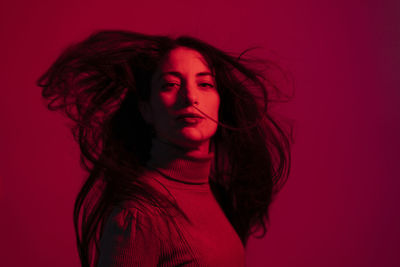 Portrait of beautiful woman against red background