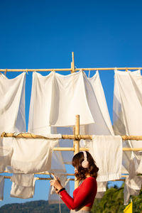 Rear view of woman on clothesline against blue sky