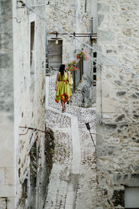 Full length of woman walking on street amidst buildings