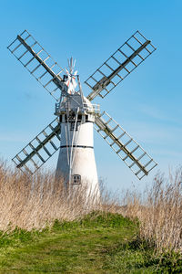 Traditional windmill on field against sky