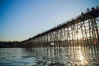 Bridge over river by building against blue sky
