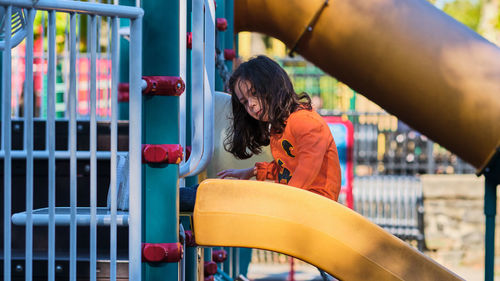 Cute young girl on a slide in a local playground