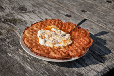 Swedish waffle with cloudberry jam and whipped cream outdoors in the autumn sun