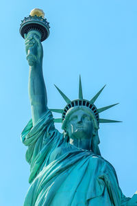 Low angle view of statue of liberty against blue sky