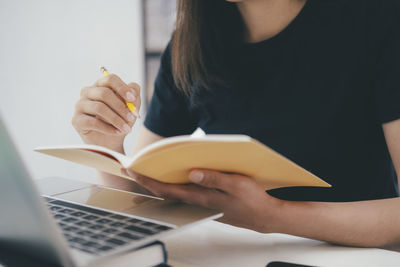 Midsection of woman using laptop on table