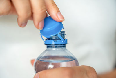 Cropped hand holding bottle against white background