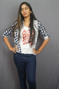 Portrait of beautiful young woman standing against wall