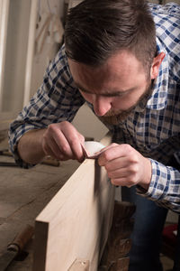 Carpenter sanding wooden plank