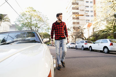 Man wearing plaid shirt while walking on road